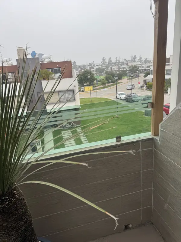 Balcón con barandal de cristal y vista a área verde