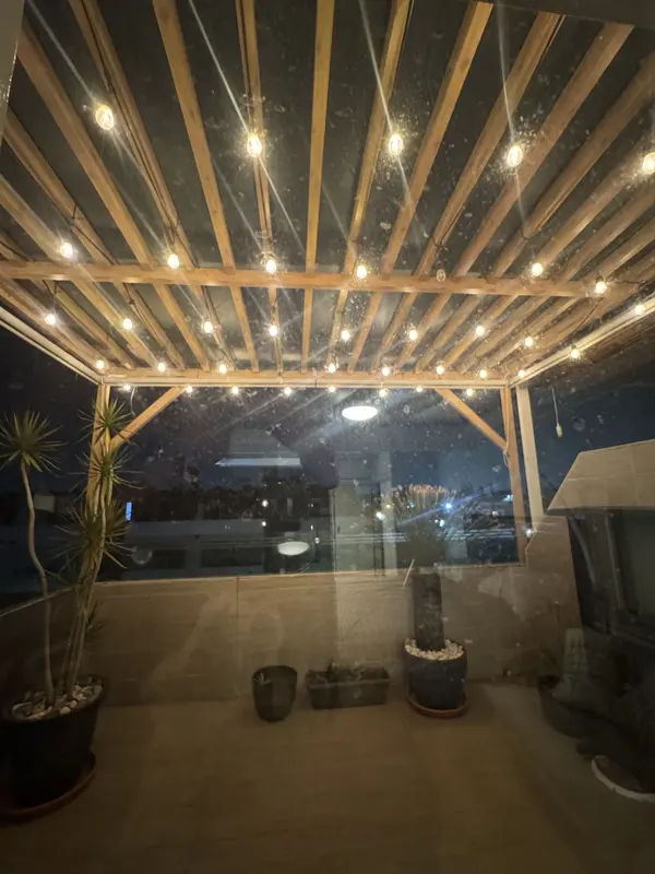 Terraza con pérgola y luces colgantes de noche